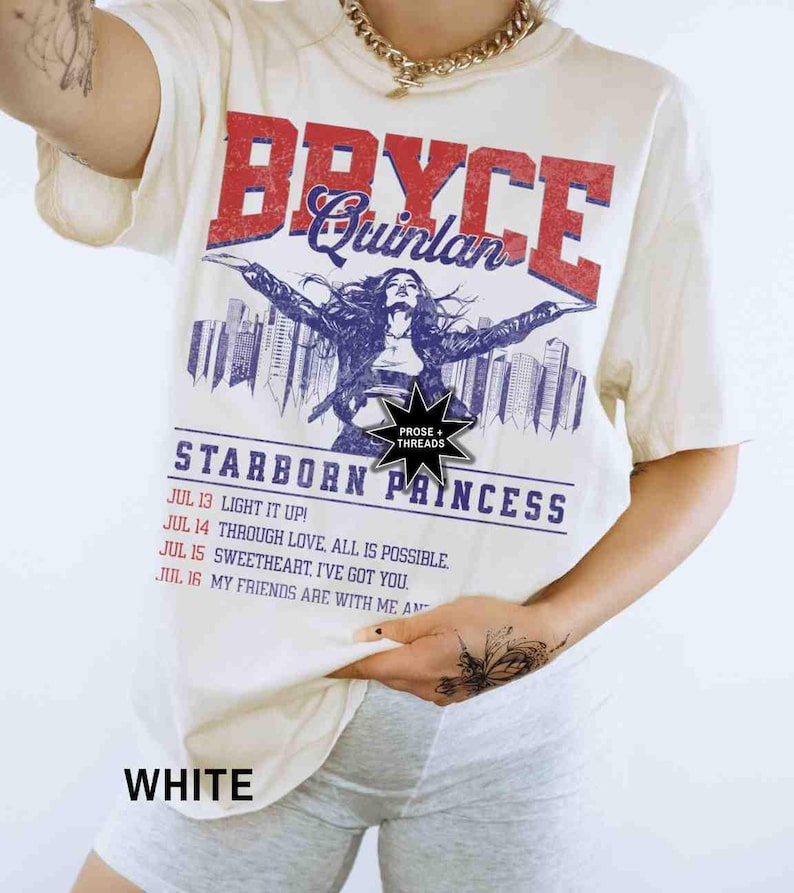 May include: White t-shirt featuring a graphic print of a woman in a city skyline. The text "Bryce Quinlan" is printed in red and blue. The text "Starborn Princess" is printed in blue. The text "Prose + Threads" is printed in black.