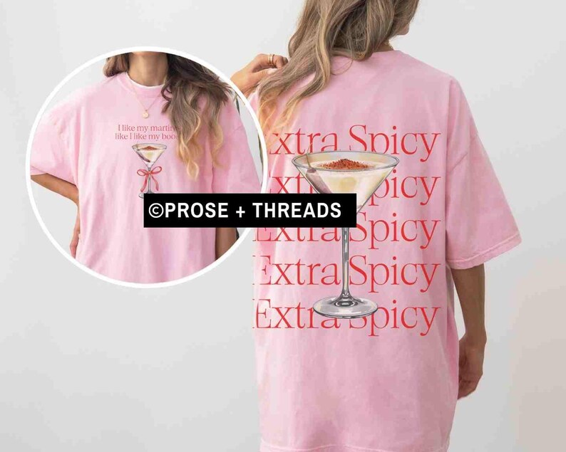 May include: A light pink t-shirt with a martini glass graphic and the text "I like my martinis like I like my boobs" on the front. The back of the shirt features the words "extra spicy" and a martini glass.