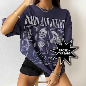 May include: Navy blue t-shirt featuring a graphic design from Shakespeare's Romeo and Juliet. The design includes a sword, skull, rose, and angel wing. The text "ROMEO AND JULIET" and "Verona" are also visible.
