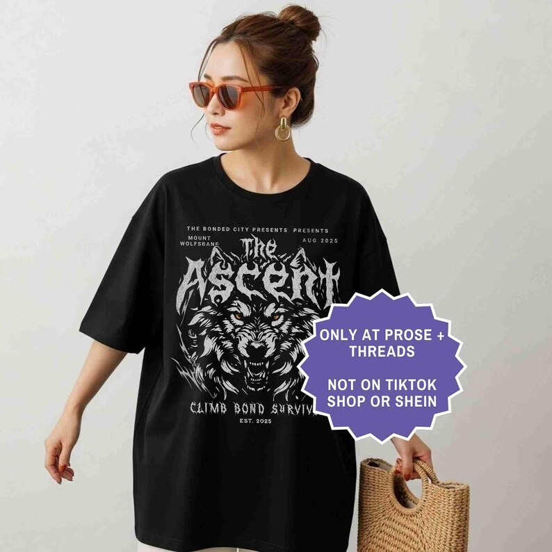 May include: Black t-shirt featuring a wolf graphic with the text "The Ascent" and "Climb Bond Surviv". The shirt also includes the text "The Bonded City Presents" and "Mount Wolfsbane".