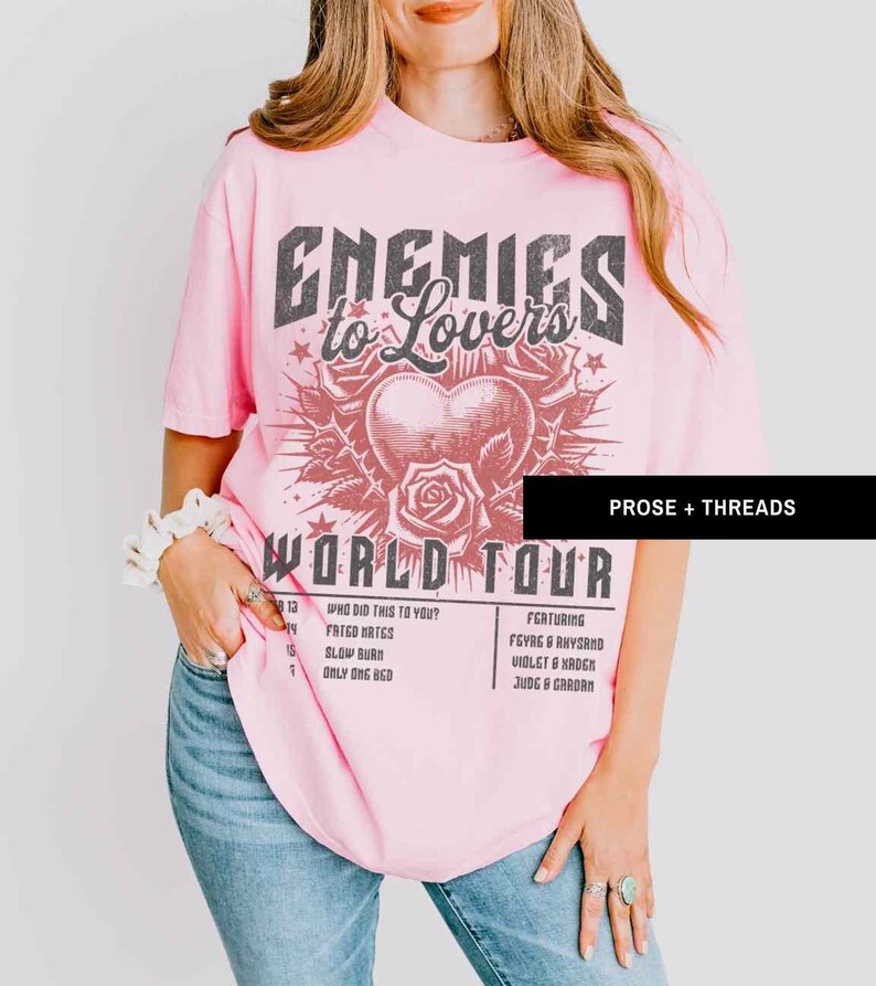 Pode incluir: Camiseta rosa com uma estampa gr&aacute;fica de um cora&ccedil;&atilde;o com espinhos e o texto "Enemies to Lovers World Tour" com uma lista de t&iacute;tulos de m&uacute;sicas e artistas. O texto "Prose + Threads" est&aacute; no canto superior direito.