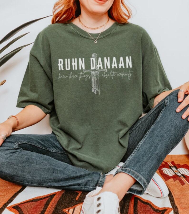 May include: A green t-shirt with a white graphic design featuring a cross and the text "RUHN DANAAN knew three things with absolute certainty".