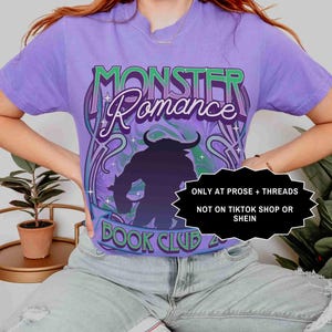 Op de afbeelding: Een paars T-shirt met de tekst "MONSTER Romance BOOK CLUB" in een gestileerd lettertype en een monster silhouet. De tekst "ONLY AT PROSE + THREADS NOT ON TIKTOK SHOP OR SHEIN" is ook zichtbaar.