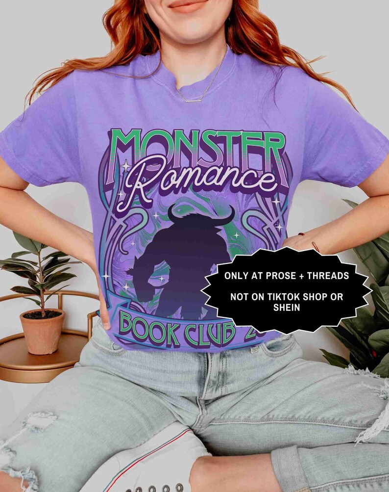 Op de afbeelding: Een paars T-shirt met de tekst "MONSTER Romance BOOK CLUB" in een gestileerd lettertype en een monster silhouet. De tekst "ONLY AT PROSE + THREADS NOT ON TIKTOK SHOP OR SHEIN" is ook zichtbaar.