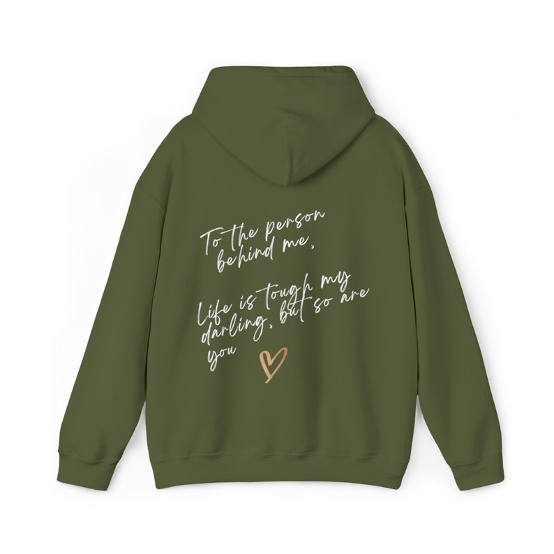 May include: Olive green hoodie with the text "To the person behind me, Life is tough my darling, but so are you" in a handwritten style, with a gold heart graphic. The hoodie has a hood and long sleeves.