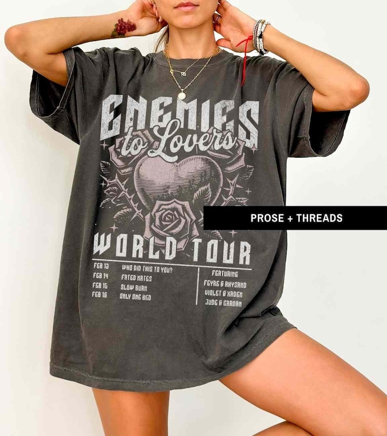 Pode incluir: Uma camiseta cinza escura de tamanho grande com uma estampa gr&aacute;fica de um cora&ccedil;&atilde;o com espinhos e uma rosa. O texto "Enemies to Lovers World Tour" est&aacute; impresso na camiseta. As datas da turn&ecirc; e os artistas que participam est&atilde;o listados abaixo do gr&aacute;fico. O texto "Prose + Threads" est&aacute; impresso no canto inferior direito da camiseta.