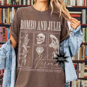 May include: Brown t-shirt featuring the text "ROMEO AND JULIE" with illustrations of a sword, skull, rose, and angel wing. The shirt also includes the text "Verona" and a quote from the play. The shirt is a vintage style.