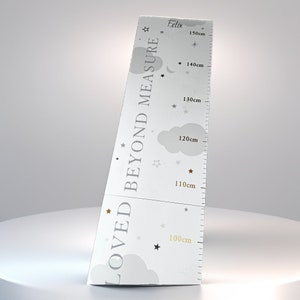 Puede incluir: Un gráfico de crecimiento blanco con un diseño de estrellas grises y doradas. El gráfico está etiquetado como "Loved Beyond Measure" y "Felix". El gráfico mide de 100 cm a 150 cm.