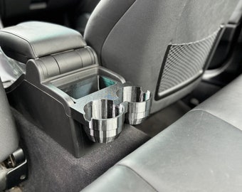 May include: A black and gray car cup holder insert, designed to fit into a car's center console. The insert features two cup holders and is made of a 3D-printed material. The cup holder is shown installed in a car interior.