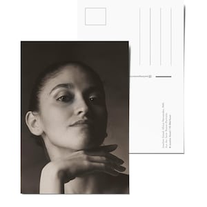 May include: Black and white portrait photograph of a woman with her chin resting on her hand. The woman is looking up and to the right.