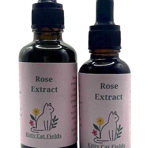 May include: Two glass bottles of Rose Extract with black droppers. The labels are pink with the text "Rose Extract" and "Kitty Cat Fields", along with a cat illustration and flowers.