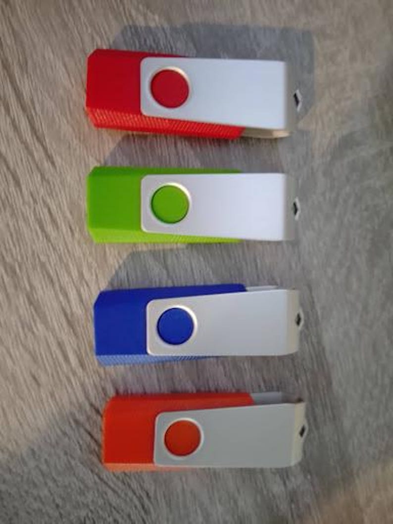May include: Four USB flash drives arranged vertically, each featuring a colored plastic body in red, lime green, blue, or orange, paired with a swiveling silver metal protective cover that has a circular cutout revealing the color underneath.