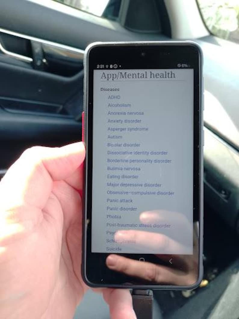 May include: A black smartphone displaying a list titled App/Mental health with a sub-heading for Diseases. The screen shows a vertical list of various mental health conditions including ADHD, Alcoholism, Anorexia nervosa, Anxiety disorder, and others.