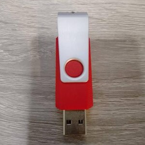 Puede incluir: Una unidad flash USB roja y blanca con un conector USB plateado. La unidad tiene un cuerpo rojo con una cubierta giratoria blanca y un bot&oacute;n circular rojo. La unidad USB es un dispositivo de almacenamiento de datos.