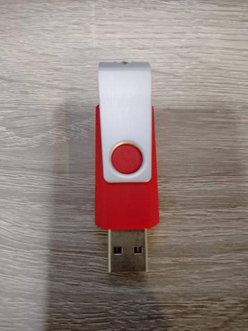 Puede incluir: Una unidad flash USB roja y blanca con un conector USB plateado. La unidad tiene un cuerpo rojo con una cubierta giratoria blanca y un bot&oacute;n circular rojo. La unidad USB es un dispositivo de almacenamiento de datos.