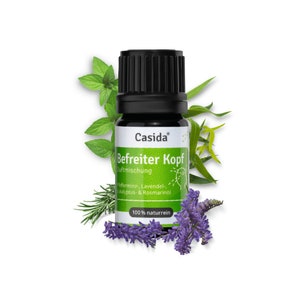 Könnte beinhalten: Eine kleine dunkelbraune Glasflasche mit schwarzem Verschluss und Etikett mit der Aufschrift "Casida Befreiter Kopf Duftmischung Pfefferminz, Lavendel, Eukalyptus & Rosmarinöl 100% naturrein". Die Flasche ist von grünen Blättern und lila Lavendelblüten umgeben.