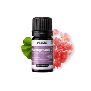 Pode incluir: Um pequeno frasco de vidro castanho escuro com uma tampa preta, etiquetado com "Casida® Rosengeranie Öl Pelargonium graveolens Ätherisches Öl in therapeutischer Qualität 100% naturrein". O frasco está rodeado de flores cor-de-rosa e verdes.