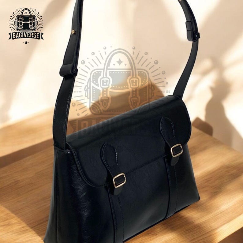 May include: A black leather satchel bag with a long adjustable strap. The bag has two gold buckles and a flap closure.