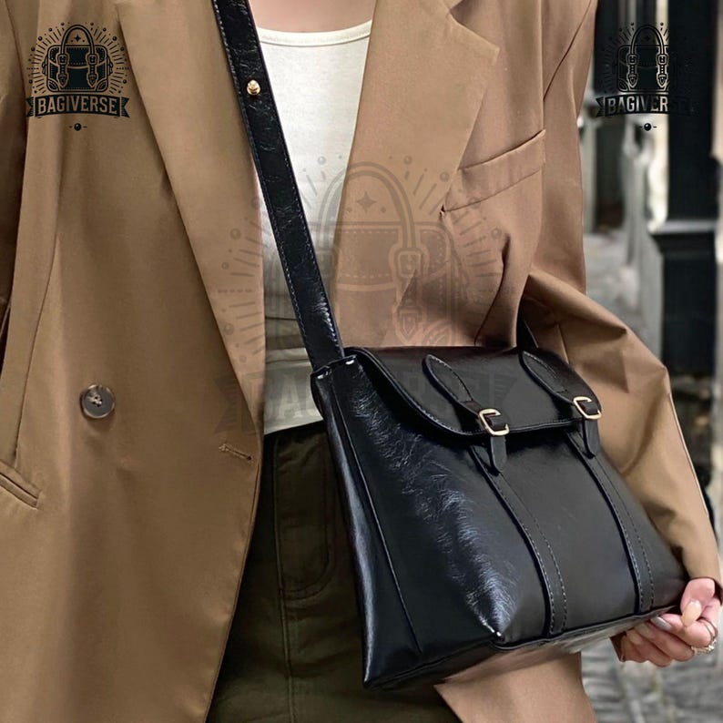 May include: A black leather crossbody bag with a flap closure and gold buckles. The bag is worn over a brown blazer and green pants.