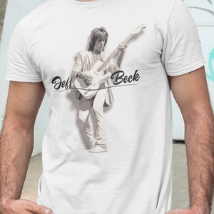 May include: A white t-shirt with a black and white image of Jeff Beck playing a guitar. The text "Jeff Beck" is written in cursive below the image.