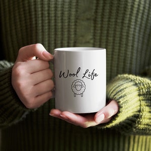 May include: White ceramic mug with a black sheep illustration and the text "Wool Life" in black cursive writing.