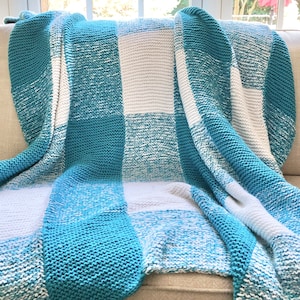 May include: A blue and white checkered knitted throw blanket draped over a couch.