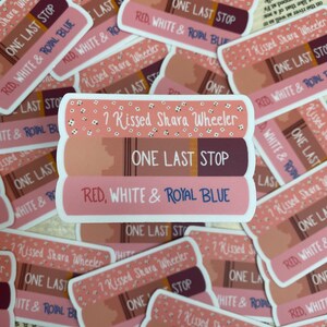 May include: A stack of three book-shaped stickers with the title "One Last Stop" and the text "Red, White & Royal Blue" on the bottom sticker. The top sticker has the text "? Kissed Shara Wheeler" on it.
