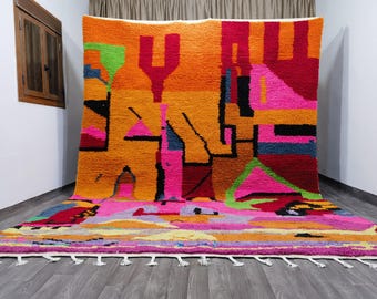 May include: A colorful abstract rug with geometric shapes in shades of pink, orange, yellow, green, and blue. The rug has a fringe border and is made of wool.