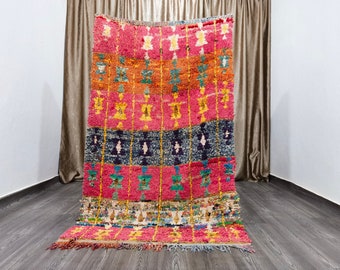 May include: A colourful Moroccan rug with a geometric pattern in shades of pink, blue, yellow, and orange. The rug has a fringe border and is made of wool.