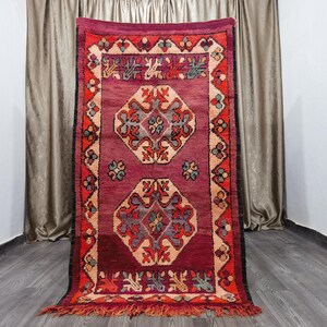 May include: A red, orange and blue patterned rug with a geometric design. The rug has a fringed border.