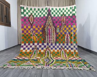 May include: A colorful Moroccan rug with a geometric pattern and a central design of stylized flames. The rug is made of wool and has a fringe border.