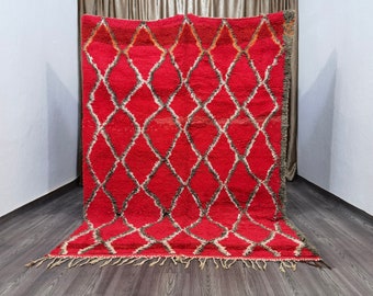 May include: A red Moroccan rug with a diamond pattern in white and gray. The rug has fringe on the edges.