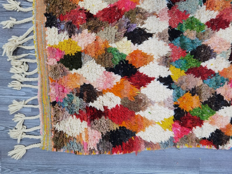May include: A colorful Moroccan rug with a geometric pattern. The rug is made of wool and has a fringe border.