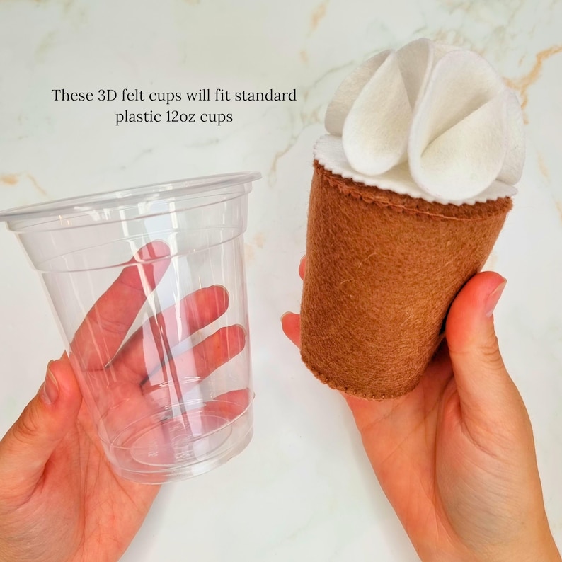 Puede incluir: Una taza de fieltro marr&oacute;n con glaseado de fieltro blanco en la parte superior. La taza de fieltro se muestra junto a una taza de pl&aacute;stico transparente de 12 oz. "Estas tazas de fieltro 3D se ajustan a las tazas de pl&aacute;stico est&aacute;ndar de 12 oz" est&aacute; escrito en la imagen.