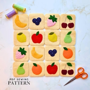 May include: A set of sixteen square felt patches featuring various fruit designs including bananas, blueberries, strawberries, cherries, lemons, apples, pears, and oranges. Two spools of thread and orange scissors are placed near the felt squares.