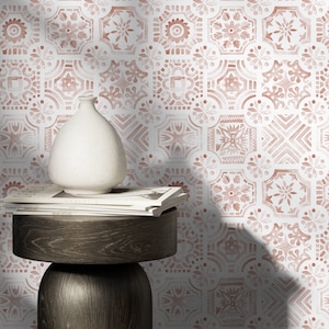 May include: A white ceramic vase sits on a wooden side table with a stack of magazines. The wall behind the table is covered in a pink and white patterned wallpaper with a geometric design.