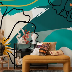 May include: A contemporary living room with a mustard yellow bench, patterned cushions, and decorative items. The backdrop is an abstract teal and white mural with black line art. A black metal shelf displays books and a black pot.