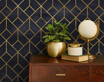 May include: A dark blue geometric wallpaper with gold lines in a repeating pattern. A wooden dresser with a gold base holds a potted plant, a globe, and a decorative jar. The overall theme is Art Deco.