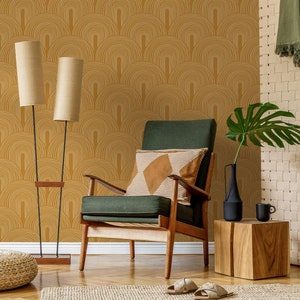 以下が含まれることがあります： マスタードイエローの壁紙に、白い幾何学模様のアーチが描かれている。緑色のアームチェアには、茶色と白のストライプのクッションが置かれている。壁紙の前にアームチェアが置かれ、隣には、黒い花瓶とマグカップが置かれた木製のサイドテーブルがある。