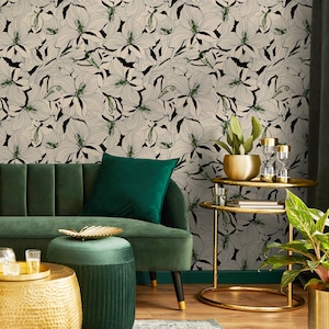 May include: A green velvet sofa with a green velvet ottoman and a gold metal side table with two tiers. The wall behind the sofa is covered in a black and white floral wallpaper.