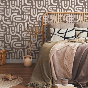 May include: A bed with a brown and white geometric patterned headboard and a brown blanket. The bed is against a wall with a brown and white geometric patterned wallpaper.