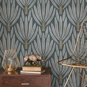 Könnte beinhalten: Türkisfarbene Tapete mit einem sich wiederholenden Muster aus stilisierten, hellgrauen floralen Formen und goldenen Akzenten. Eine goldfarbene Drahtrahmenlampe, eine geometrische Bärenskulptur und ein goldfarbener Stuhl deuten auf ein modernes Innendesign-Thema hin.