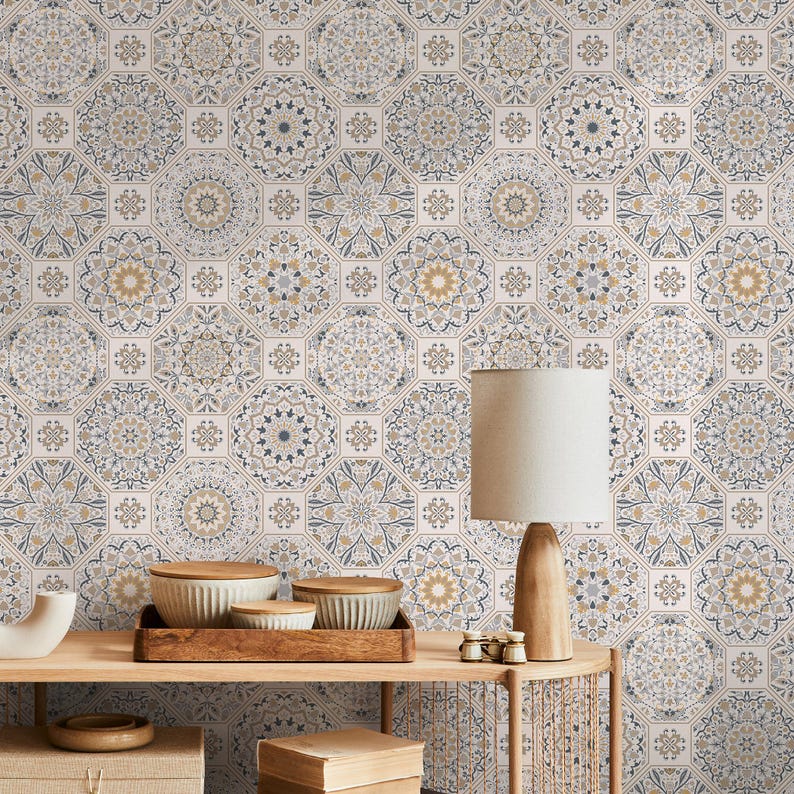 May include: A white wall with a repeating pattern of blue and gold geometric shapes. A wooden table with a lamp, bowls, and other decorative items sits in front of the wall.