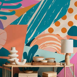 May include: A colorful abstract wall mural with teal, orange, and pink shapes. A wooden console table displays white ceramic vases, bowls, and a lamp with a beige shade. The overall theme is modern home decor.