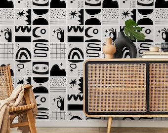 Può includere: Un interno moderno con una parete geometrica a motivi bianchi e neri. In primo piano, una sedia in legno con una coperta beige e un mobile moderno di metà secolo con un fronte intrecciato. Vasi decorativi e una pianta.