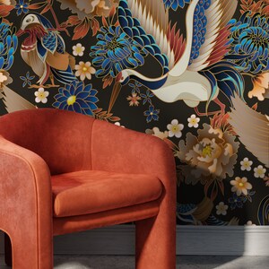 May include: An orange velvet armchair sits in front of a black background with a floral pattern. The pattern features white, blue, and gold cranes, peonies, and chrysanthemums.
