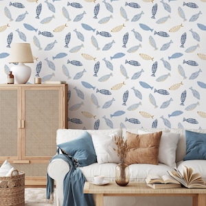 Könnte beinhalten: Eine weiße Wand mit einem sich wiederholenden Muster aus blauen und goldenen Fischen. Die Fische sind stilisiert mit verschiedenen Mustern. Der Raum ist mit einem weißen Sofa, einem Holzschrank und einer Lampe eingerichtet.