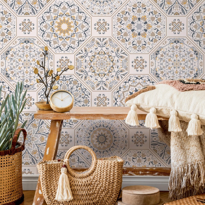 May include: A white wall with patterned wallpaper featuring hexagonal tiles with intricate blue and gold designs. A wooden bench with a woven bag, a clock, and a throw blanket with tassels sits in front of the wall.