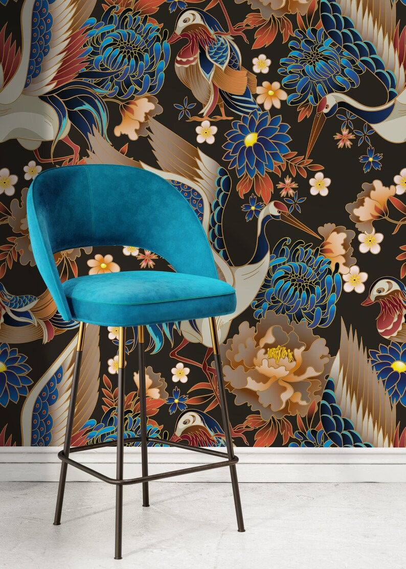 May include: A teal blue velvet bar stool with a black metal frame and gold accents. The stool is in front of a black background with a floral pattern featuring cranes, flowers, and birds.