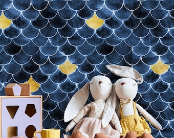 May include: A navy blue and gold scale pattern wallpaper backdrop. Two stuffed bunny dolls sit on a wooden shelf, one wearing a pink dress and the other a yellow outfit. A shape sorter and yellow mug are also on the shelf.